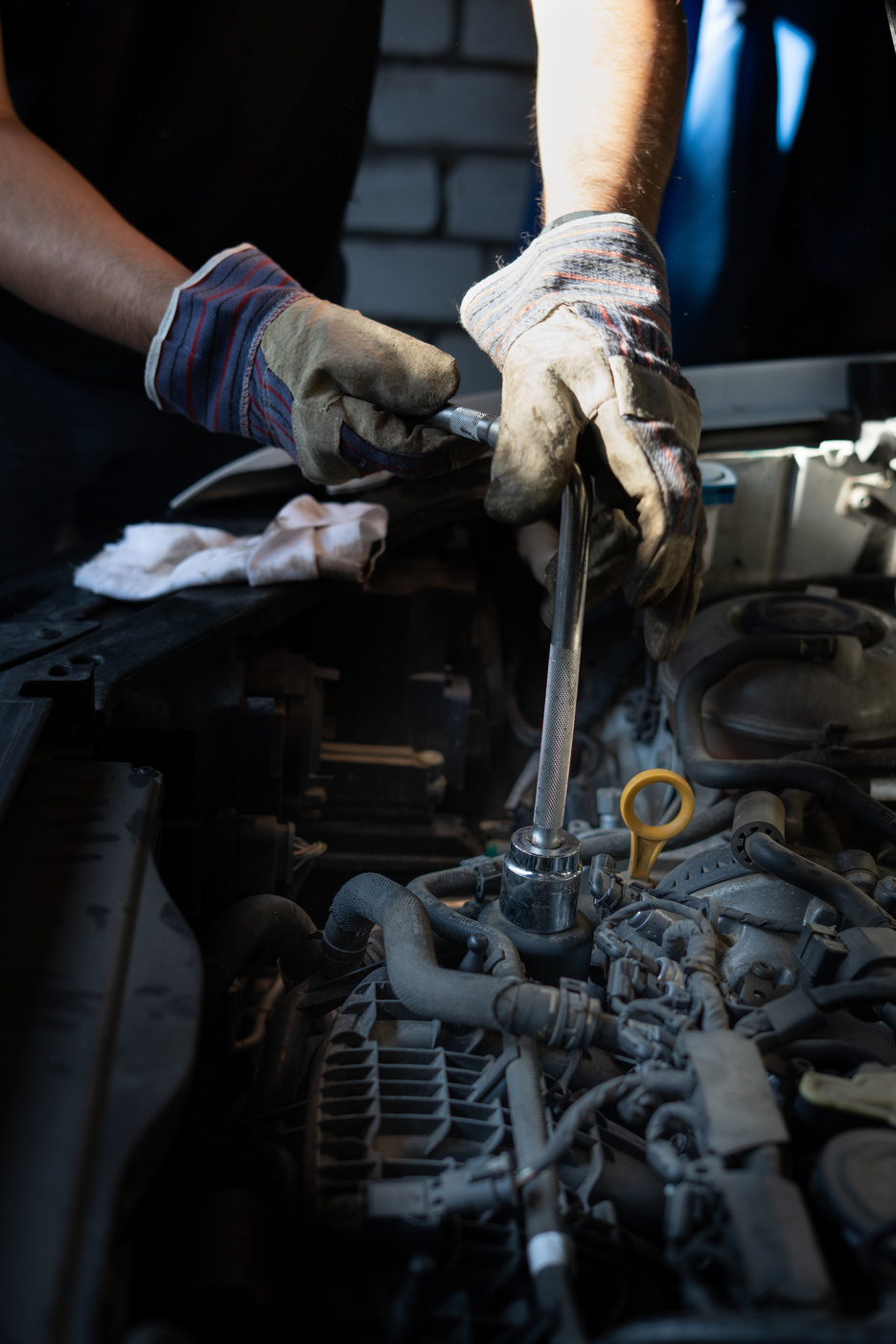 The mechanic repairs the car under the hood